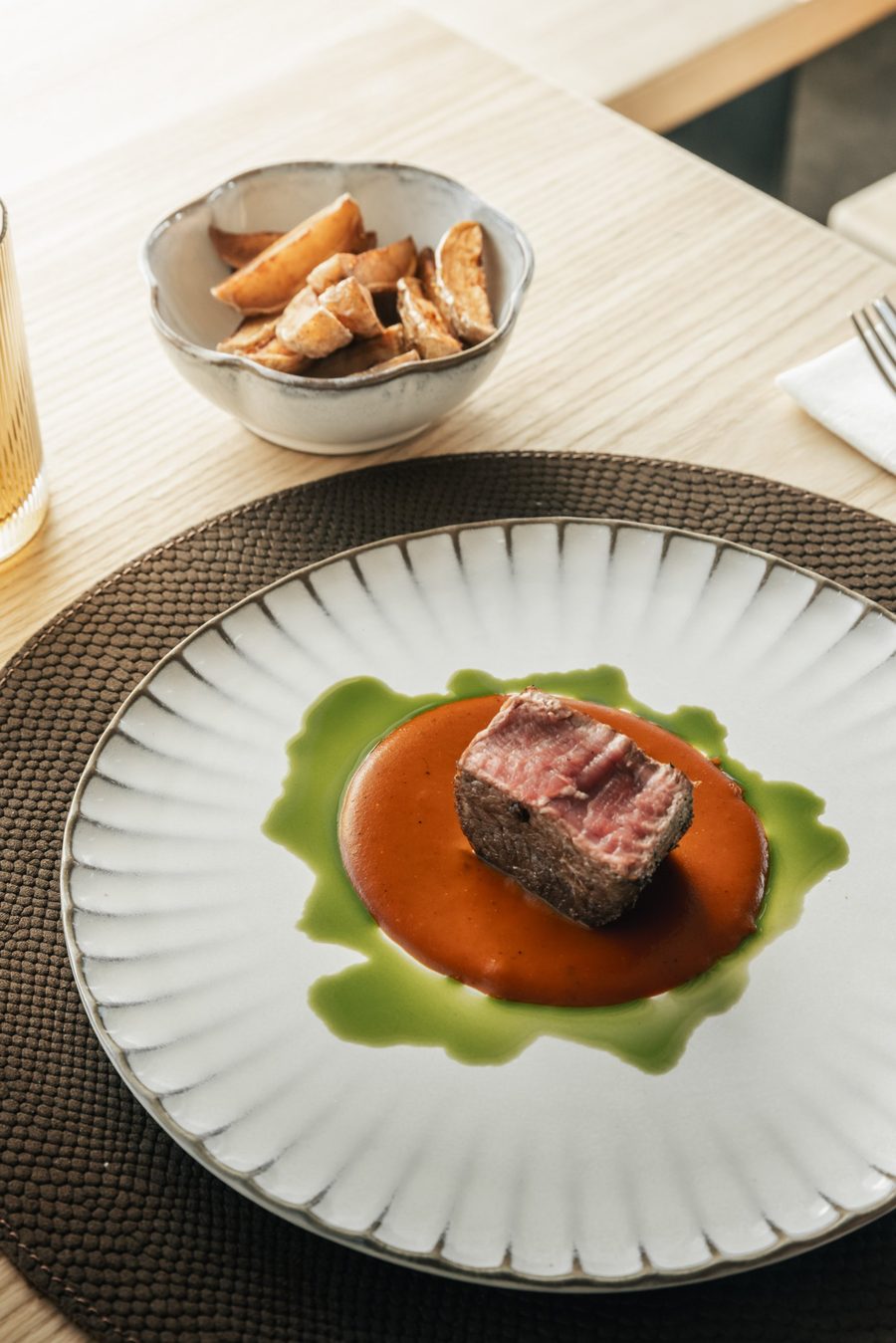 Filetto di carne rosa su crema di peperone e olio alle erbe, con patate al forno
