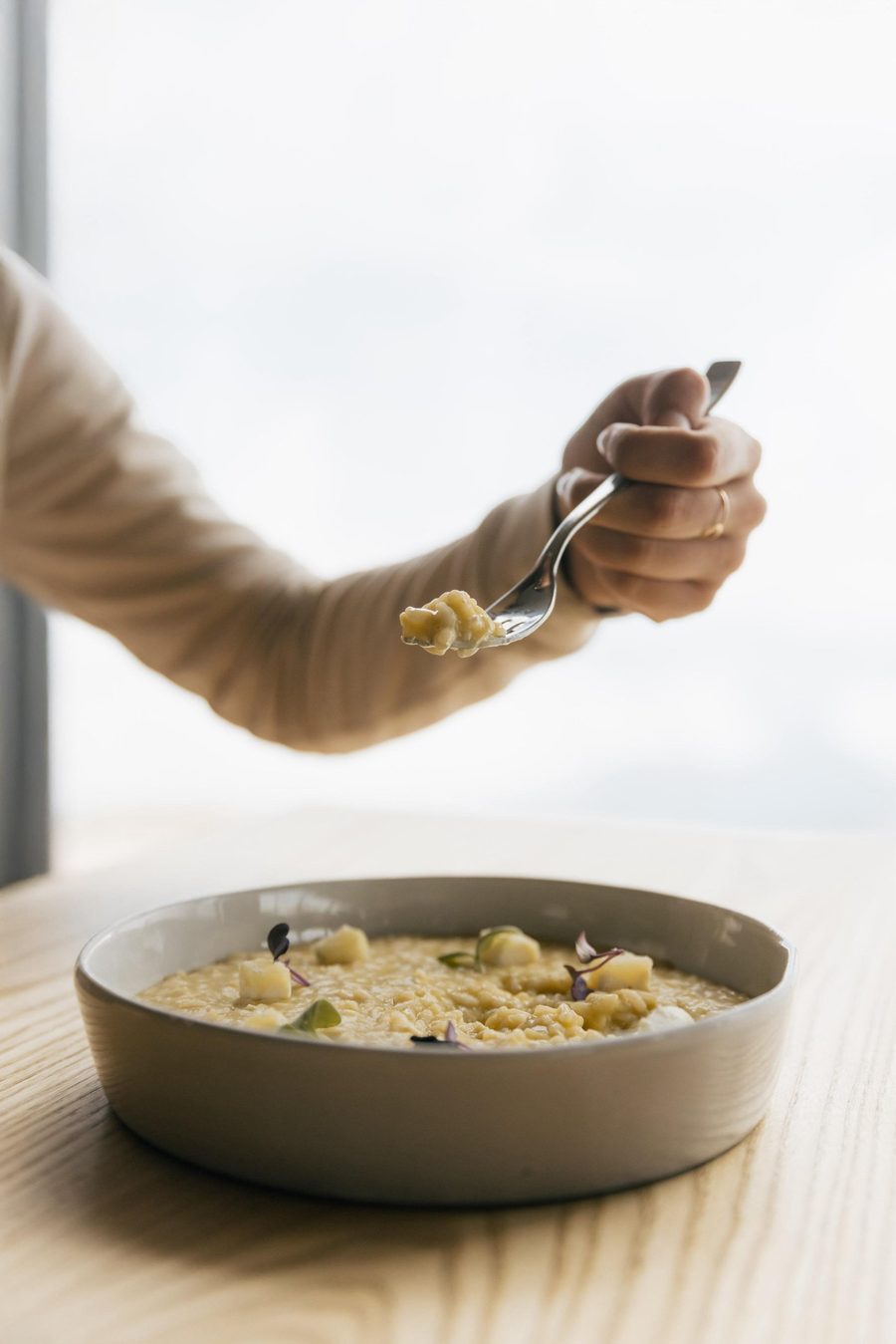 Una forchettata di risotto davanti alla vetrata del ristorante